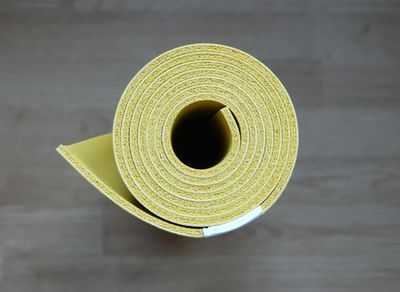 A glass of water next to a rolled up exercise mat.
