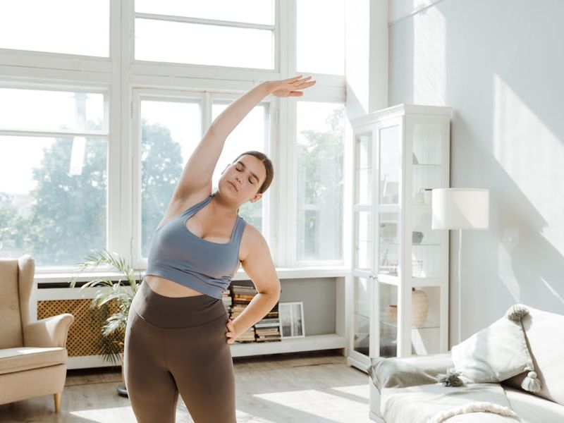 Person stretching in a bright, minimalist room.